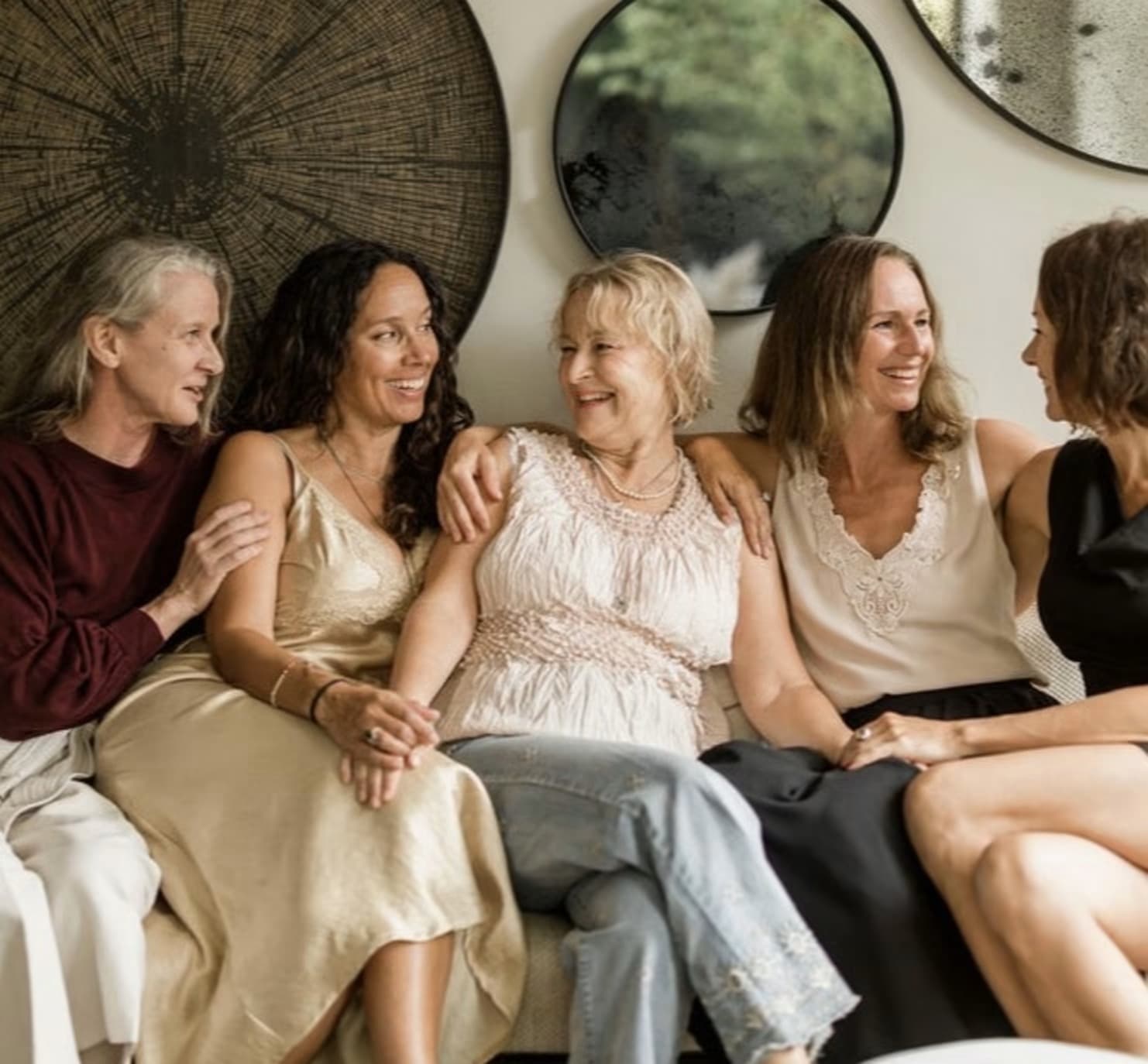 Five women laughing together on a sofa, Kristina in the middle with an arm around her neighbour