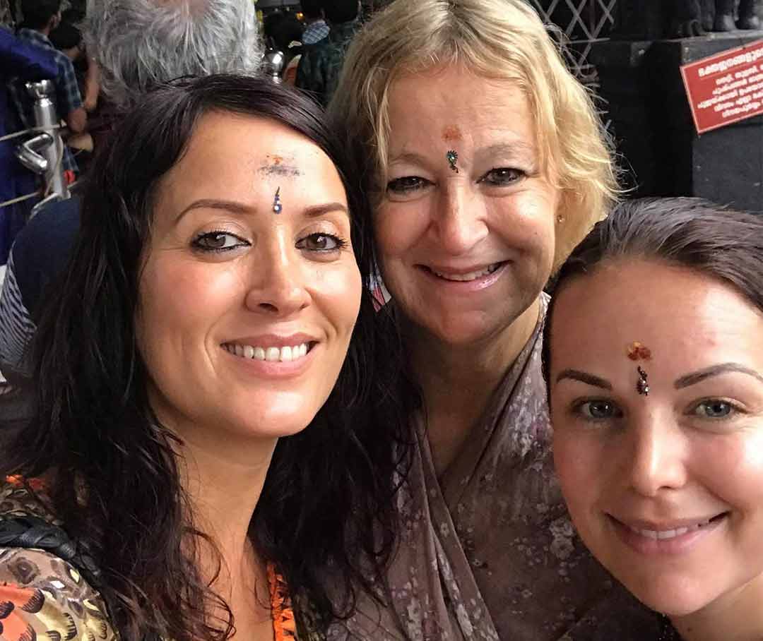 Kristina with two friends, all with bindis on their foreheads, in India